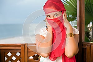 Woman in yashmak sitting in an arbour on seacoast