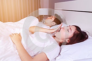 Woman yawning and her husband sleeping on bed