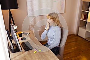 Woman yawning while sitting at her desk in an office