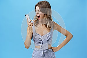 Woman yelling at smartphone with sick and tired look being agressive and angry swearing on boyfriend who dumbed her on