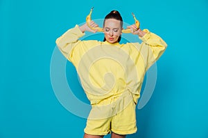 a woman in yellow clothes on a blue background with bananas in her ears