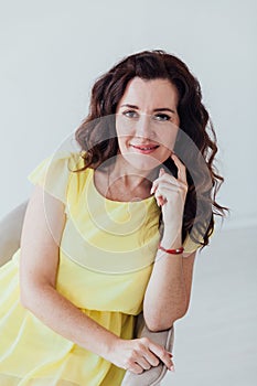 a woman in yellow clothes sits in a chair in a bright room