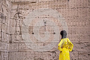 Woman in yellow dress looking at the hieroglyphs