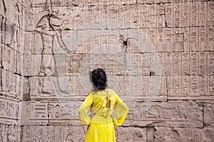 Woman in yellow dress looking at the hieroglyphs