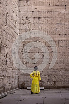 Woman in yellow dress looking at the hieroglyphs