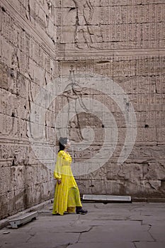 Woman in yellow dress looking at the hieroglyphs