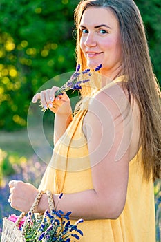 A woman in a yellow dress stands on a blooming lavender field