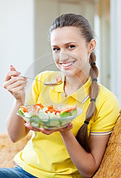 Woman in yellow eating vegetables salad