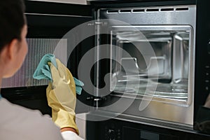 A woman in yellow gloves cleaning the oven