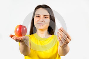 A woman in yellow holds an apple and a pill in her hands. Vitamins in natural form and in synthetic, dietary supplements