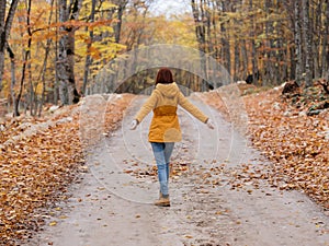 woman in yellow jacket forest road autumn traveler fresh air