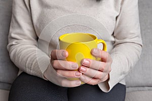 Woman with a yellow mug, commonly enjoyed for tea and coffee photo