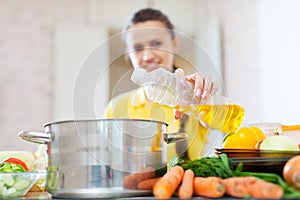 Woman in yellow pours oil from bottle