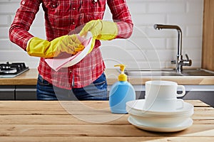 Woman in yellow protective glove with plates, dishes and cloth on kitchen. Washing and cleaning concept