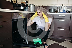 Woman in yellow protective gloves looking dirty oven at home kitchen.