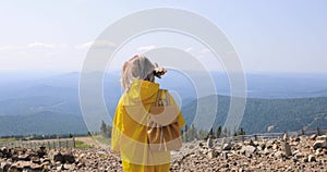 Woman in a yellow raincoat on top of a mountain. Young Woman Healthy Active Lifestyle. Adventure in Nature.