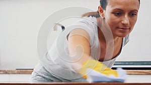 Woman in yellow rubber gloves is cleaning cooking panel in kitchen with fat remover spray and a duster. Crop. Copy space