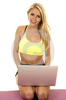 Woman yellow sports bra kneel with laptop smile