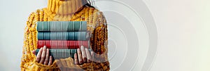 Woman in a yellow sweater holds books in her hands. Stack of classic books. White background. Banner with copy space.