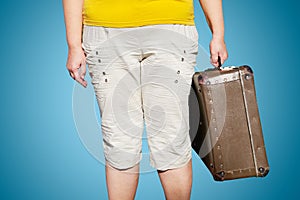 Woman in a yellow T-shirt stands with a suitcase in her hand