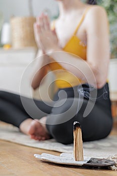 woman in a yellow top does meditation at home on mat in lotus position. lady is engaged in physical exercises