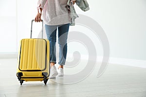 Woman with yellow travel suitcase in airport. Space for text