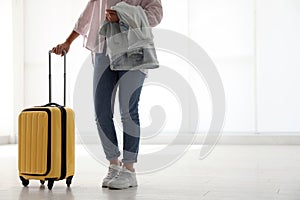 Woman with yellow travel suitcase in airport. Space for text