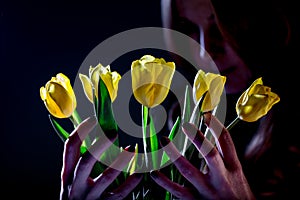 Woman with yellow tulips on dark background