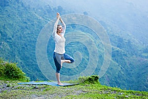 Woman in yoga asana Vrikshasana tree pose outdoors