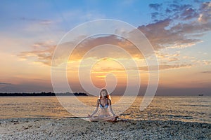 Woman in yoga lotus meditation at sunset