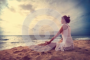 Woman yoga meditating on the ocean beach