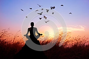 Woman yoga and meditating, silhouette on nature sunset