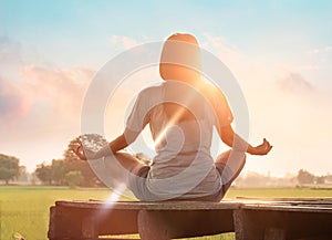 Woman yoga and meditation on wooden in sunset outdoor background
