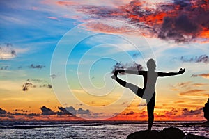 Woman in yoga pose on sea beach rock