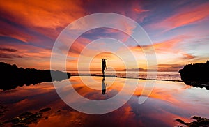 A woman in a yoga pose silhouetted against a sunset with her reflection in the water 2