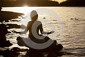 Woman yoga and lotus silhouette pose meditation and relax in the mountan lake. Healthy and Zen Concept Close up