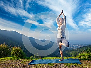 Woman in yoga Vrikshasana tree pose outdoors