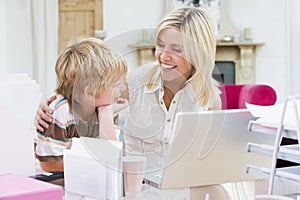 Woman and young boy in home office with laptop