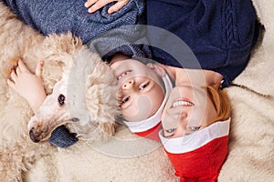 A woman with a young boy son and a dog dressed in New Year`s hats is lying on the couch and smiling. View from above