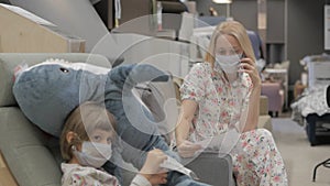 A woman with a young daughter in medical masks on her face in a shopping center