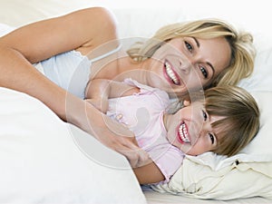 Woman and young girl in bed smiling