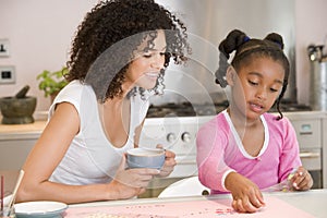 Woman and young girl in kitchen with art project s