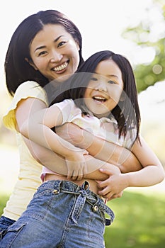 Woman and young girl outdoors embracing
