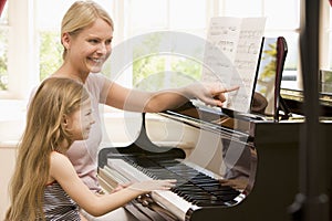 Woman and young girl playing piano and smiling