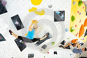 Woman and young man climbing on rock-climbing wall