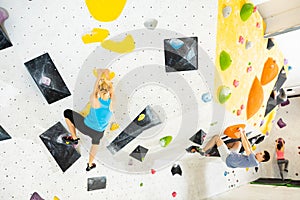 Woman and young man climbing on rock-climbing wall