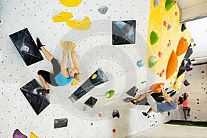 Woman and young man grabbing ledges of artificial climbing wall