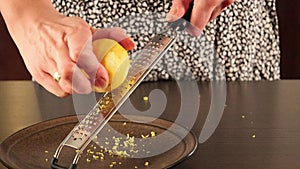 Woman zesting lemon at home closeup