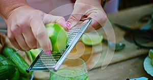 Woman zesting a lime over an iced cocktail