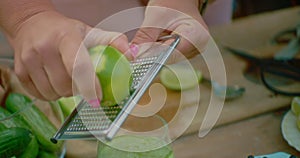 Woman zesting a lime over an iced cocktail